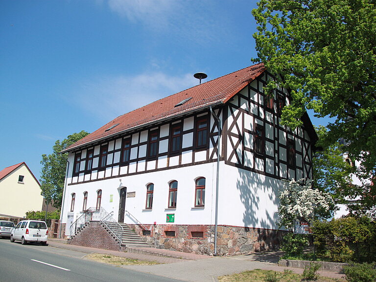 ehemalige Heideschule direkt an der Straße - heute ist ein Dorfgemeinschaftshaus, davor Parktaschen