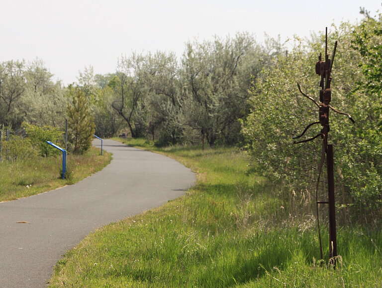 Radweg und Schrottplastik entlang des Kunstpfades am Gremminer See
