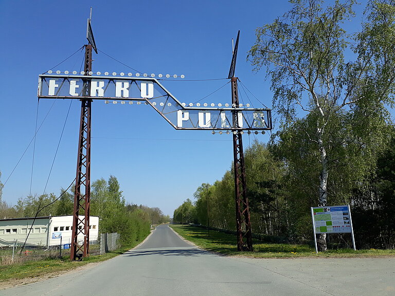 Straße zum Freilichtmuseum Ferroplis mit Willkommensschild 