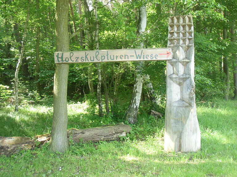 Holzschild mit Aufschrift: Holzskulpturenwiese und Pfeil in Richtung rechts