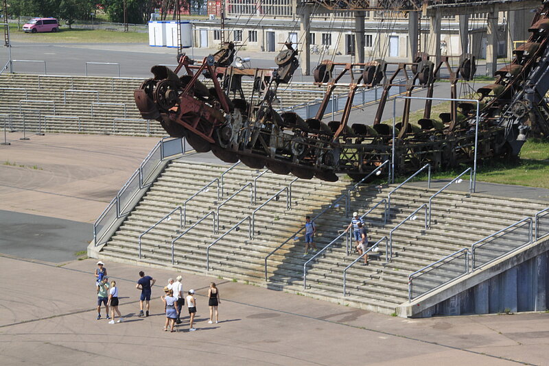 Eine Gruppe Menschen befindet sich während einer Führung in der Arena auf Ferropolis.