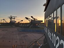 Auf der Besucherplattform eines Tagebraugroßgerätes mit Blick auf die Verastaltungsarena mit zwei weiteren Tagebaugroßgeräten im Hintergrund. Die Sonne geht gerade unter.