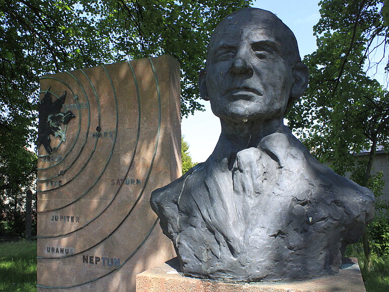 Nahaufnahme der Büste vom Galle-Denkmal und Darstellung vom Sonnensystem