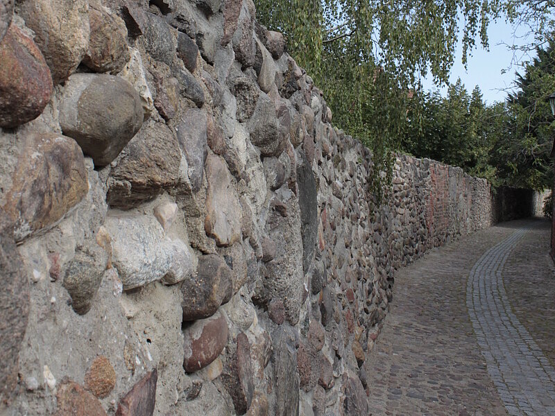 Nahaufnahme der Stadtmauer. Die Stadtmauer besteht aus vielen kleineren Findlingen.