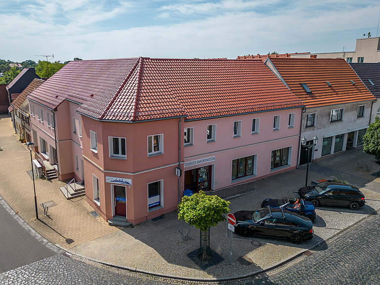 Tourist-Info aus der Lustperspektive. Parkbuchten mit parkenden Autos davor.