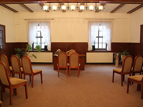 Trauzimmer im Rathaus. In der Mitte stehen Stühle für Brautpaar vor dem Tisch des Standesbeamten, links und rechts dahinter Stühle für die Gäste.